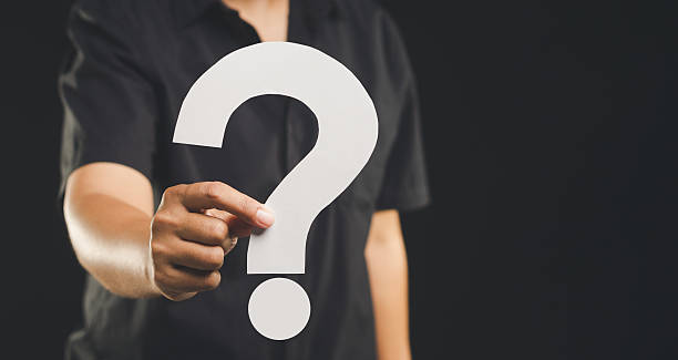 istock Hand holding a white question mark symbol against a black background. 2210818725