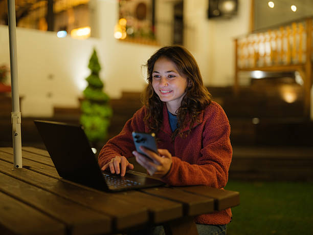 istock Woman using smartphone and laptop working on the backyard at night 2210818997
