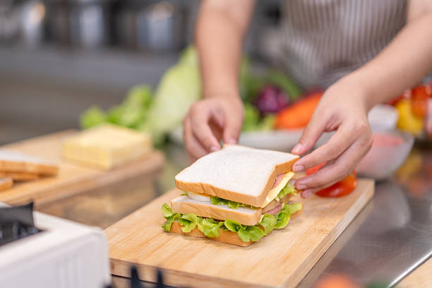 istock Hands Assembling a Fresh Sandwich on Wooden Cutting Board 2210823865