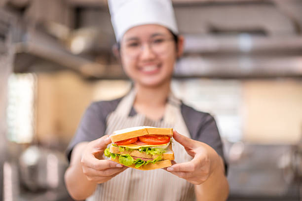 istock Smiling Young Chef Presenting a Freshly Made Sandwich in Kitchen 2210823885