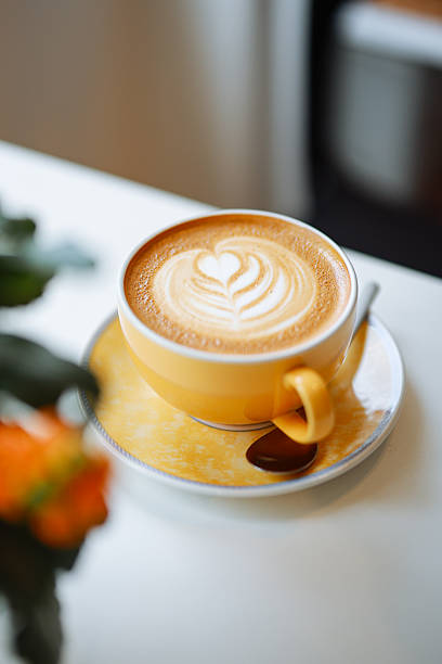 Close up hot cappuccino white coffee cup with heart shape latte art on dark brown old wood table at cafe,food and drink concept.
