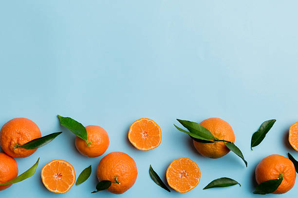 istock Many fresh ripe mandarin with green leaves on colored background, top view, space for text 2210826691