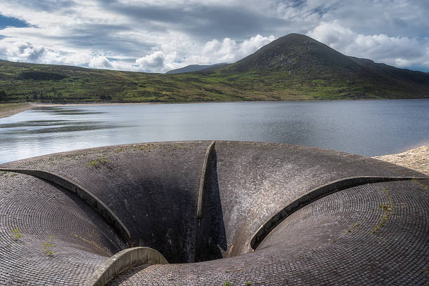 Immerse yourself in the captivating drainage systems found at a peaceful Silent Valley Reservoir, nestled among lush greenery, majestic Mourn Mountains and a beautifully dramatic sky, Northern Ireland