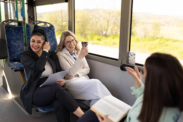 istock Three happy women sitting on a bus, doing paperwork and drinking coffee. 2210832358