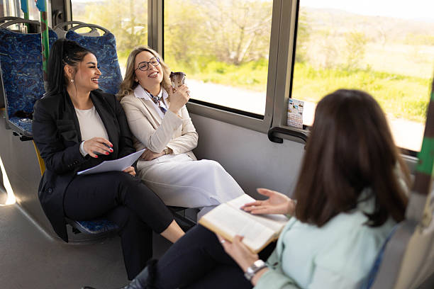 istock Three happy women sitting on a bus, doing paperwork and drinking coffee. 2210832359