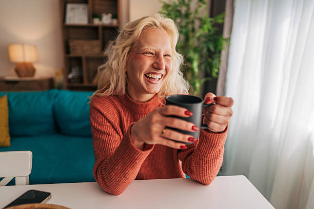 istock Happy young woman laughing while drinking coffee at home 2210834137