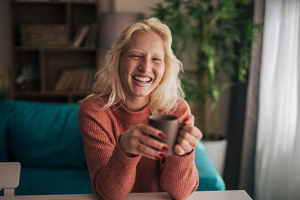 istock Young woman laughing while drinking coffee at home 2210834208