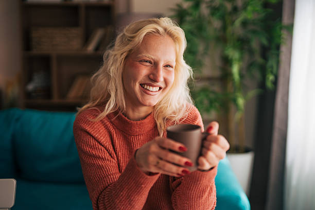 istock Smiling blonde woman drinking coffee at home 2210834210