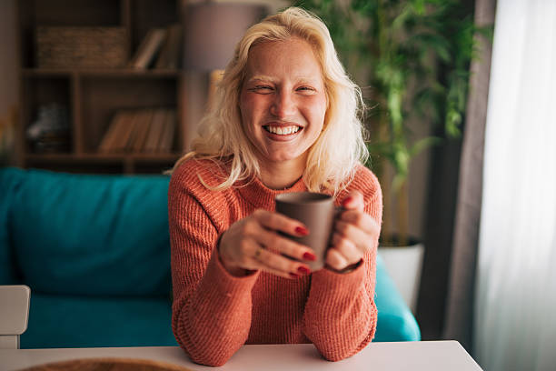 istock Smiling young woman drinking coffee at home 2210834279