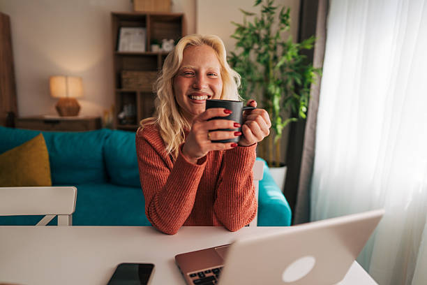istock Smiling woman drinking coffee while working from home 2210834437