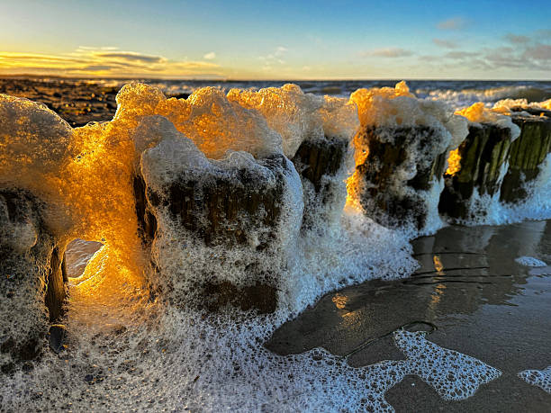 Wave breaks on the pier of the sunny Baltic Sea.