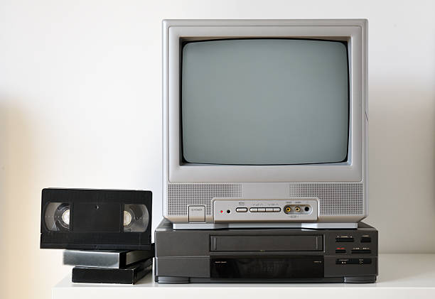 Old silver vintage TV and VCR on a shelf.
