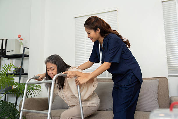 istock Elderly Support and Encouragement. A caregiver assists an elderly patient with using a walker, providing motivation and comfort. 2210843915