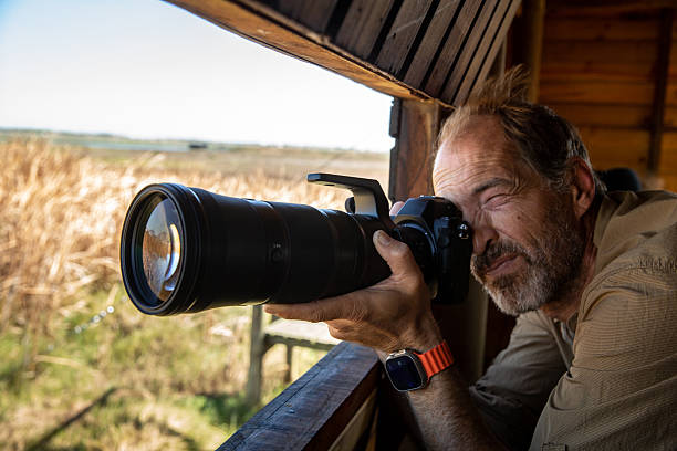 istock Photographer birdwatching and capturing images from a bird hide 2210844265