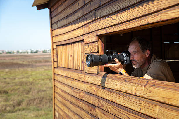 istock Photographer birdwatching and capturing images from a bird hide 2210844276