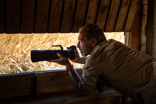 istock Photographer birdwatching and capturing images from a bird hide 2210844277