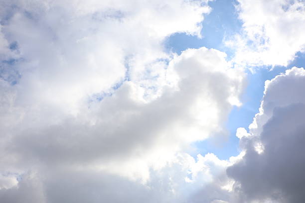 A vibrant sky filled with fluffy clouds, showcasing sunlight breaking through, creating a serene atmosphere.