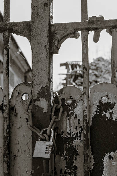 istock A rusty metal gate secured with a thick chain and a combination padlock. 2210848050