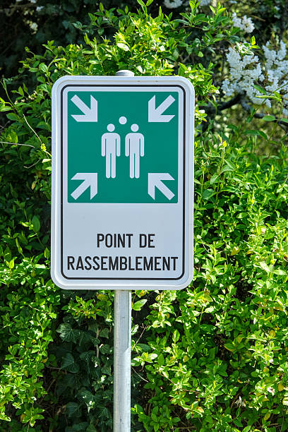 istock Emergency assembly point sign in French, displayed outdoors with green foliage background. 2210848057