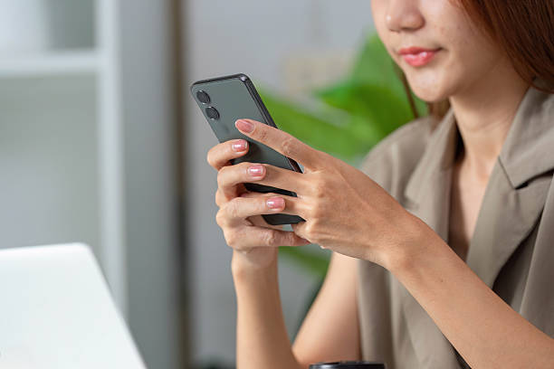 Mobile Technology and Communication. A woman engaging with her smartphone while seated at her desk.