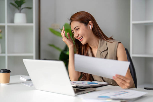 istock Work Online and Virtual Meetings. A young professional engages in a video call, expressing joy and excitement while reviewing documents. 2210851067