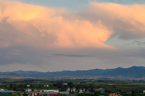 a cloudy sunset and a mountain in darkness.