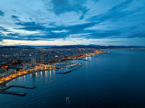 Aerial view of illuminated Barcelona beach and city skyline at blue hour
