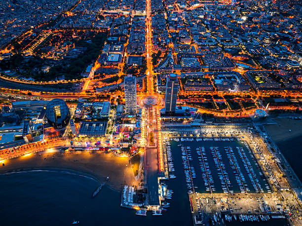 Overhead night view of Port Olimpic marina and city lights along the beach