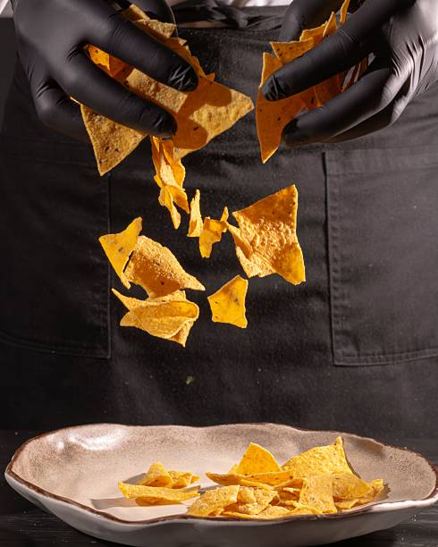 istock Crispy tortilla chips falling from hands kitchen setting food photography indoor lighting close-up shot culinary art 2210857185
