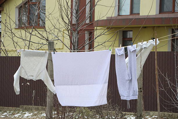 An outdoor clothesline with freshly washed white laundry delicately hanging amidst a picturesque winter scenery