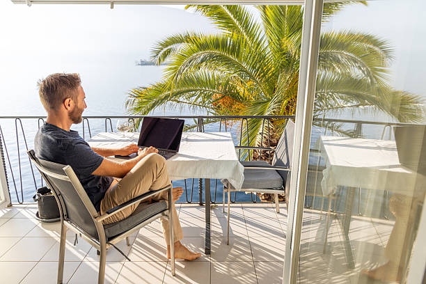 istock Man Working on Laptop on a Sunny Seaside Balcony 2210859605