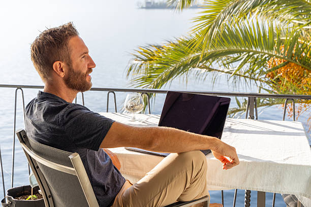 istock Man Working on Laptop on a Sunny Seaside Balcony 2210859611