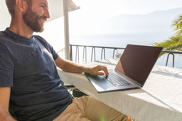 istock Man enjoying remote work with laptop by the lakeside 2210859642