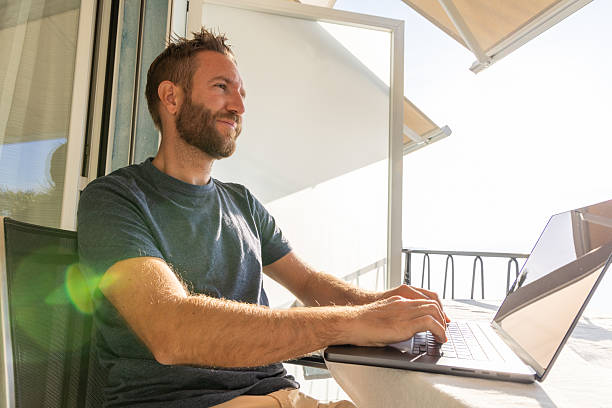 Man Working on Laptop at Lakeside Balcony