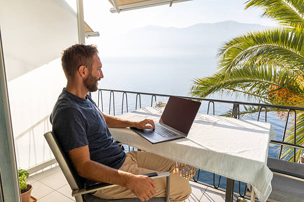 istock Man enjoying remote work with laptop by the lakeside 2210859669