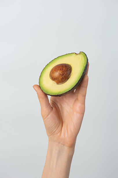 istock Half of an avocado in a woman's hand 2210861857