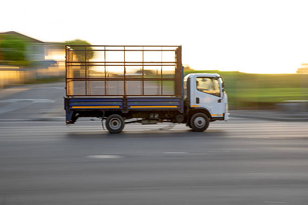 Industrial middle duty day powerful cab compact white rig semi truck with chrome parts and big box trailer standing on the urban city street making the local delivery for different business needs