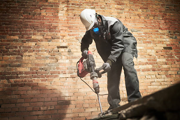 Low angle shot of African American demolishing old cement floor in room with brick walls