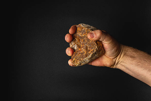 istock Hand holding a rock against a dark background 2210864660