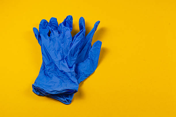 istock Blue gloves on vibrant yellow background showing cleanliness 2210865223
