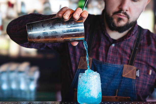 istock Bartender pouring a fresh blue cocktail drink from a cocktail shaker into a glass filled with crushed ice 2210869233