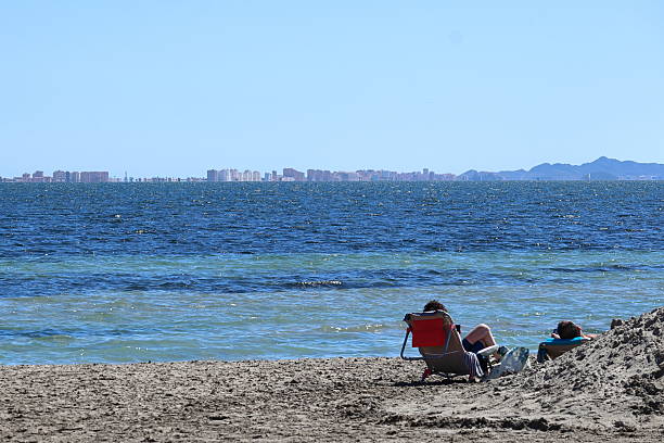An umbrella and some people bathing in the sea.