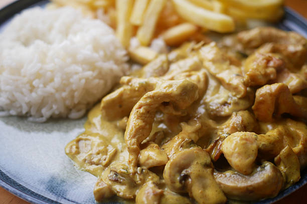 Savor a delicious chicken curry served with fluffy rice and crispy fries for a satisfying meal