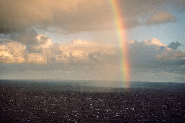 Madeira seascapes. Close-up view of beautiful rainbow that arches over the vast ocean waves beneath cloudy sky, creating scenic and serene atmosphere. Dreamlike