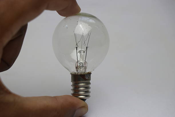Cropped Hand Holding Electric Bulb Against Black Background
