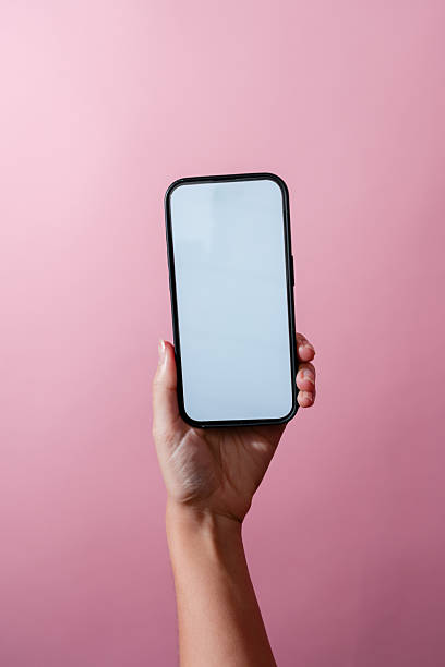 istock Woman holding smartphone with blank white screen on pink background 2210873377
