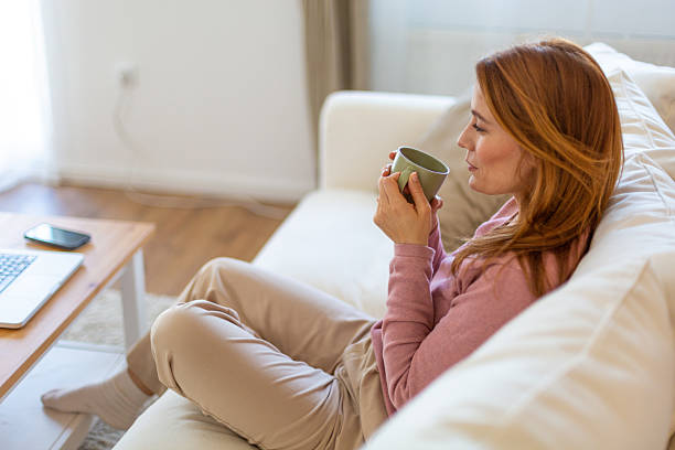 istock Woman relaxing on sofa drinking tea after work 2210880823