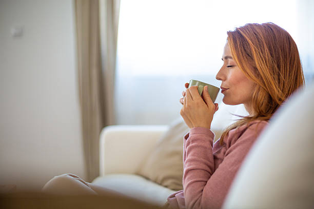 istock Serene woman enjoying a warm beverage on sofa at home 2210880892