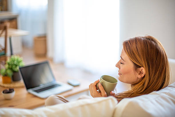 istock Woman relaxing on sofa enjoying a cup of coffee after work 2210881186