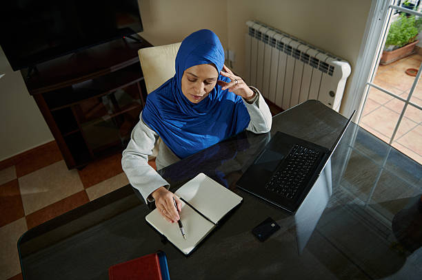 istock Woman Working Remotely with Laptop and Notebook in Home Office Setting 2210884388